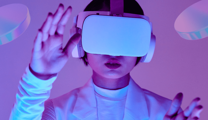 A person wearing a VR headset interacts with a virtual environment, surrounded by futuristic, glowing shapes. The scene represents the immersive experience of the metaverse. The image is used to convey the concept of digital innovation, highlighting Vertech Digital's focus on the future of virtual spaces and technology.